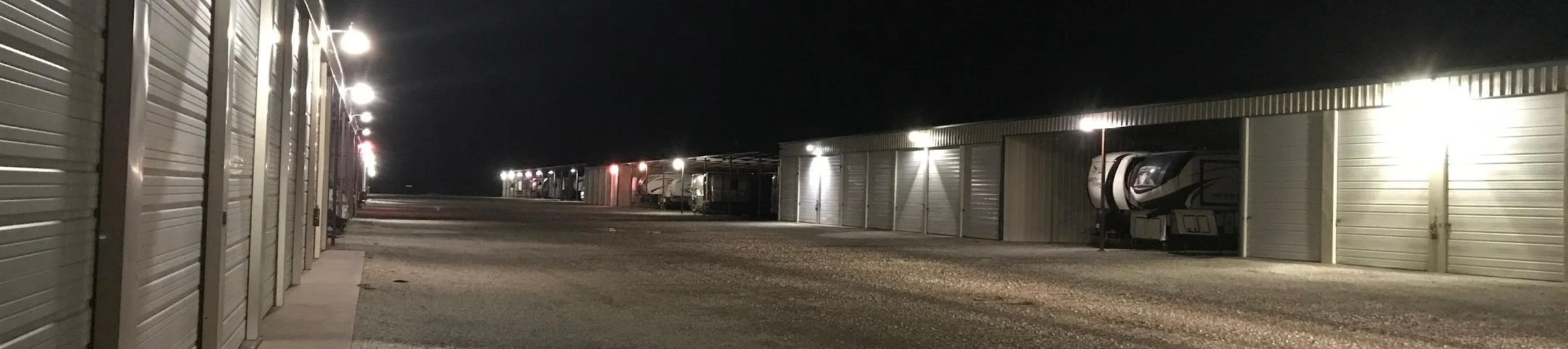 A drive lane at RV Storage and More lit at night by overhead lights on every building